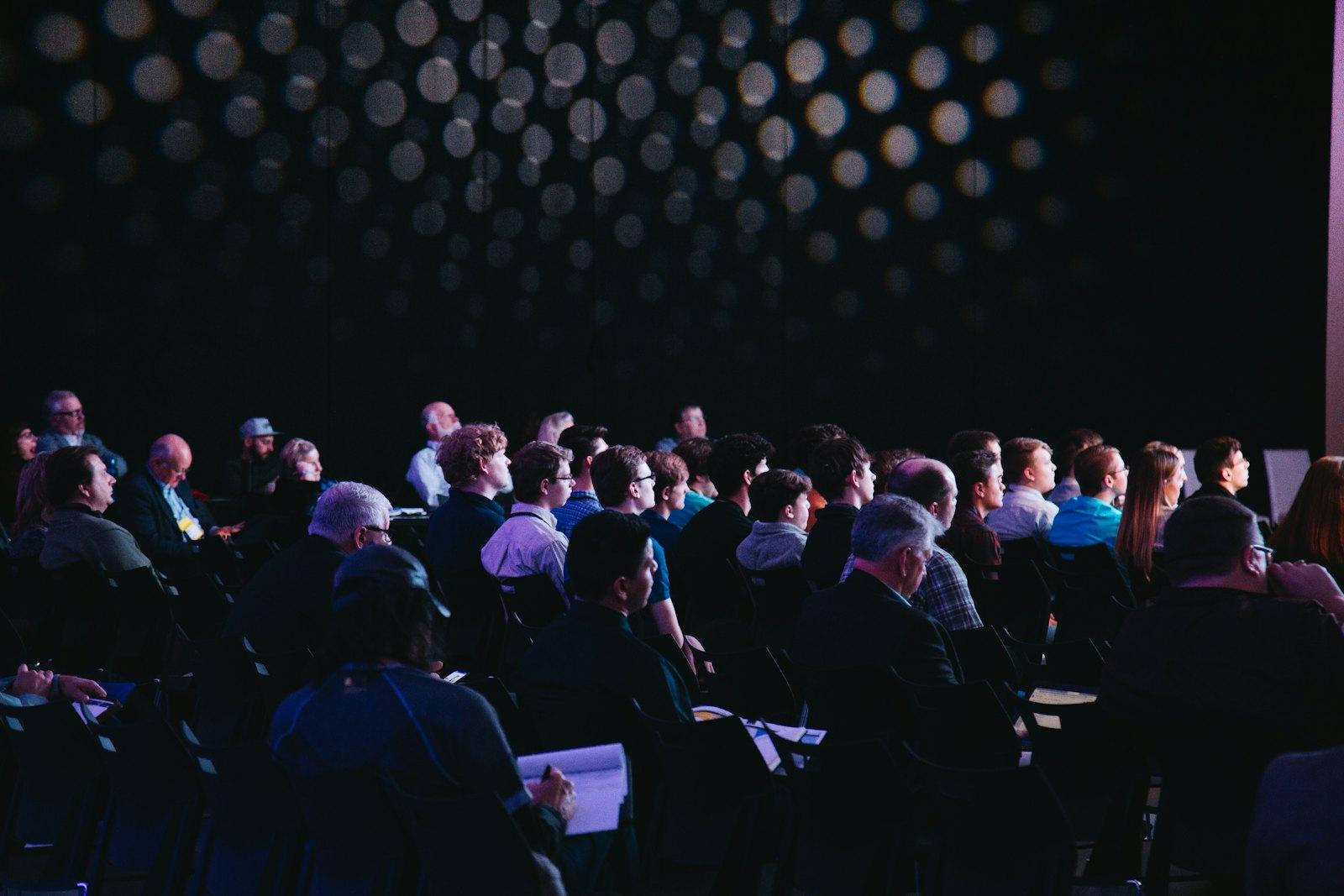 A seated audience taking notes during a conference session