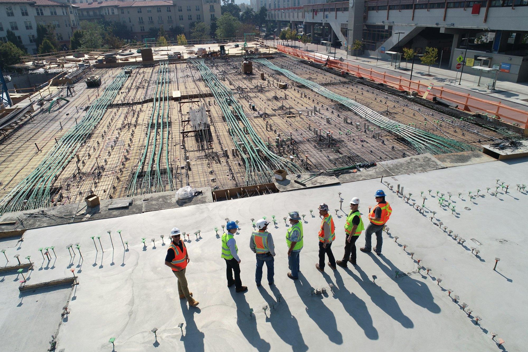 A team of engineers in hard hats and high-visibility vests reviewing a site from above