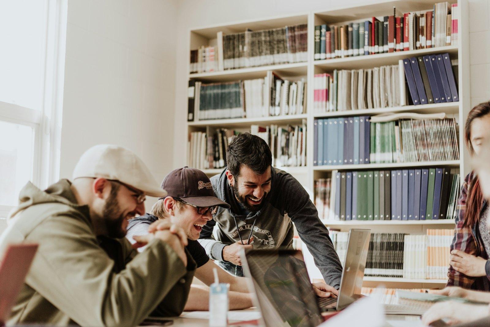 A group of students collaborating around a laptop in a library