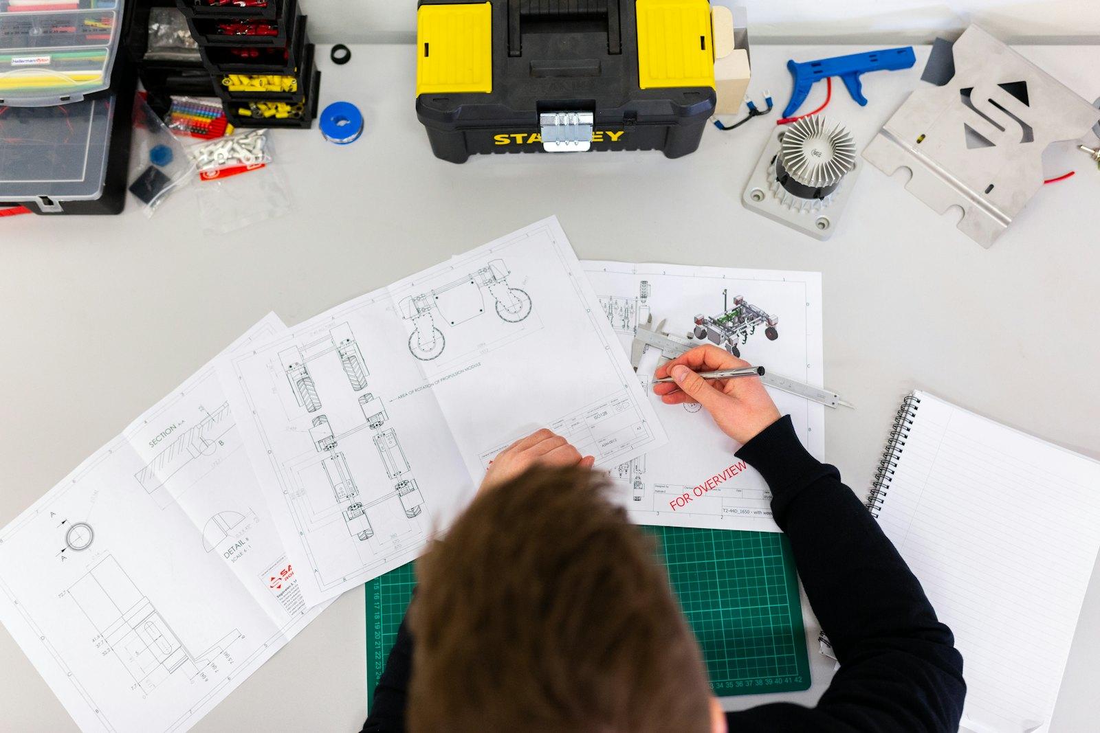 An engineer marking up technical drawings at a drafting desk